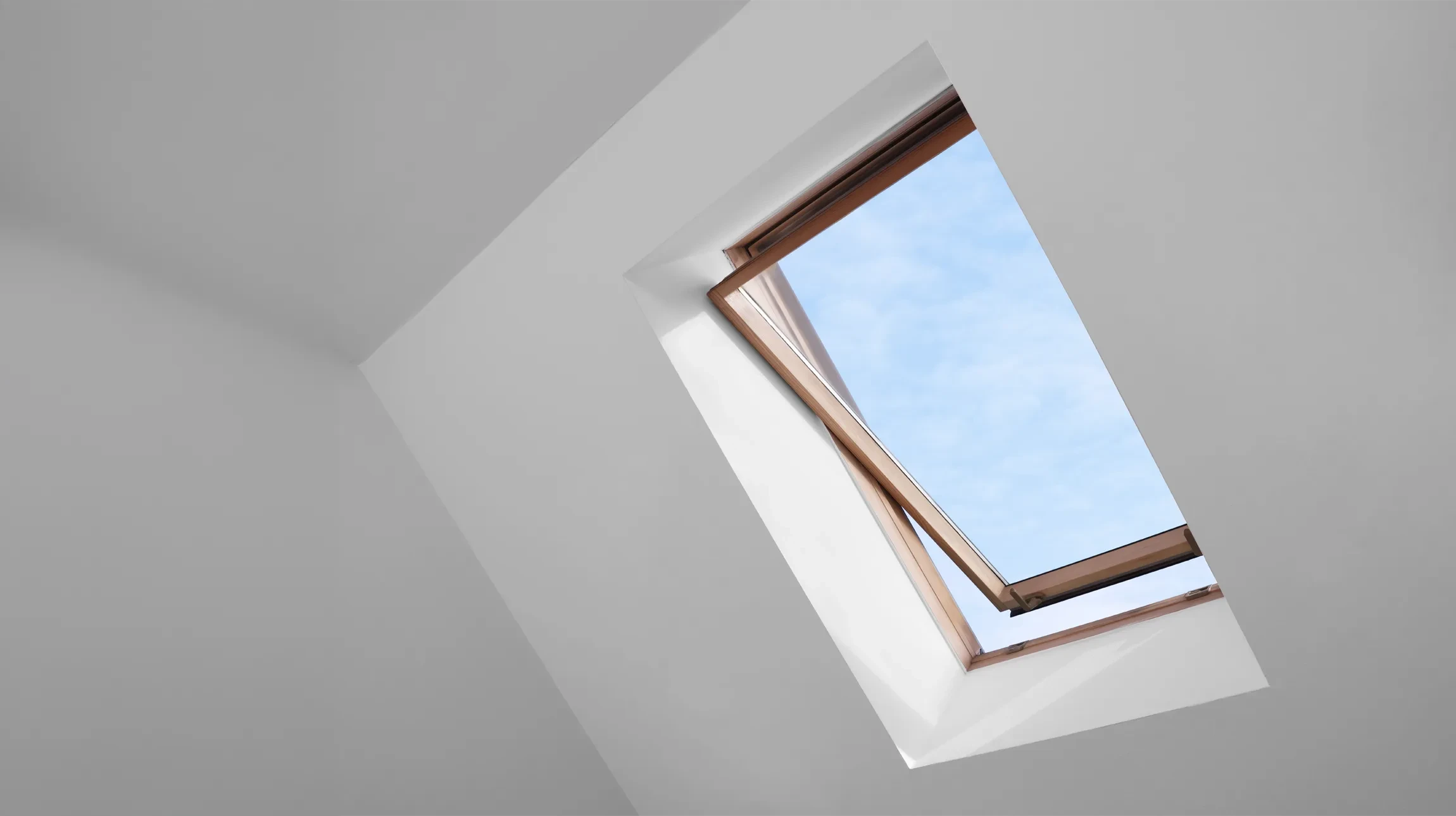 Fenêtre ouverte sur le toit de la lucarne sur plafond incliné dans la chambre mansardée