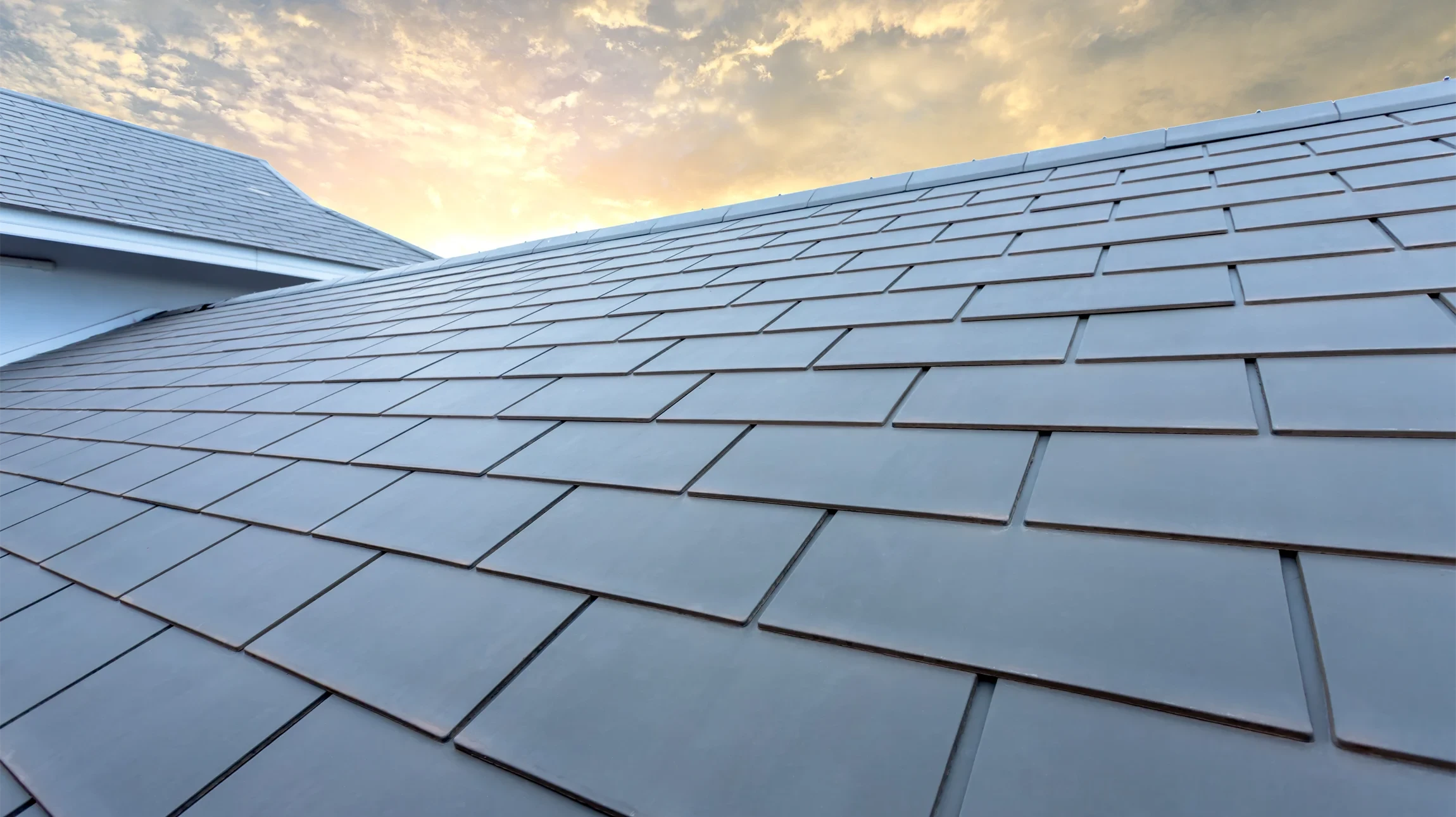 Maison traditionnelle alpine en bois avec toit en tuiles rouges, balcon fleuri et façade blanche au rez-de-chaussée