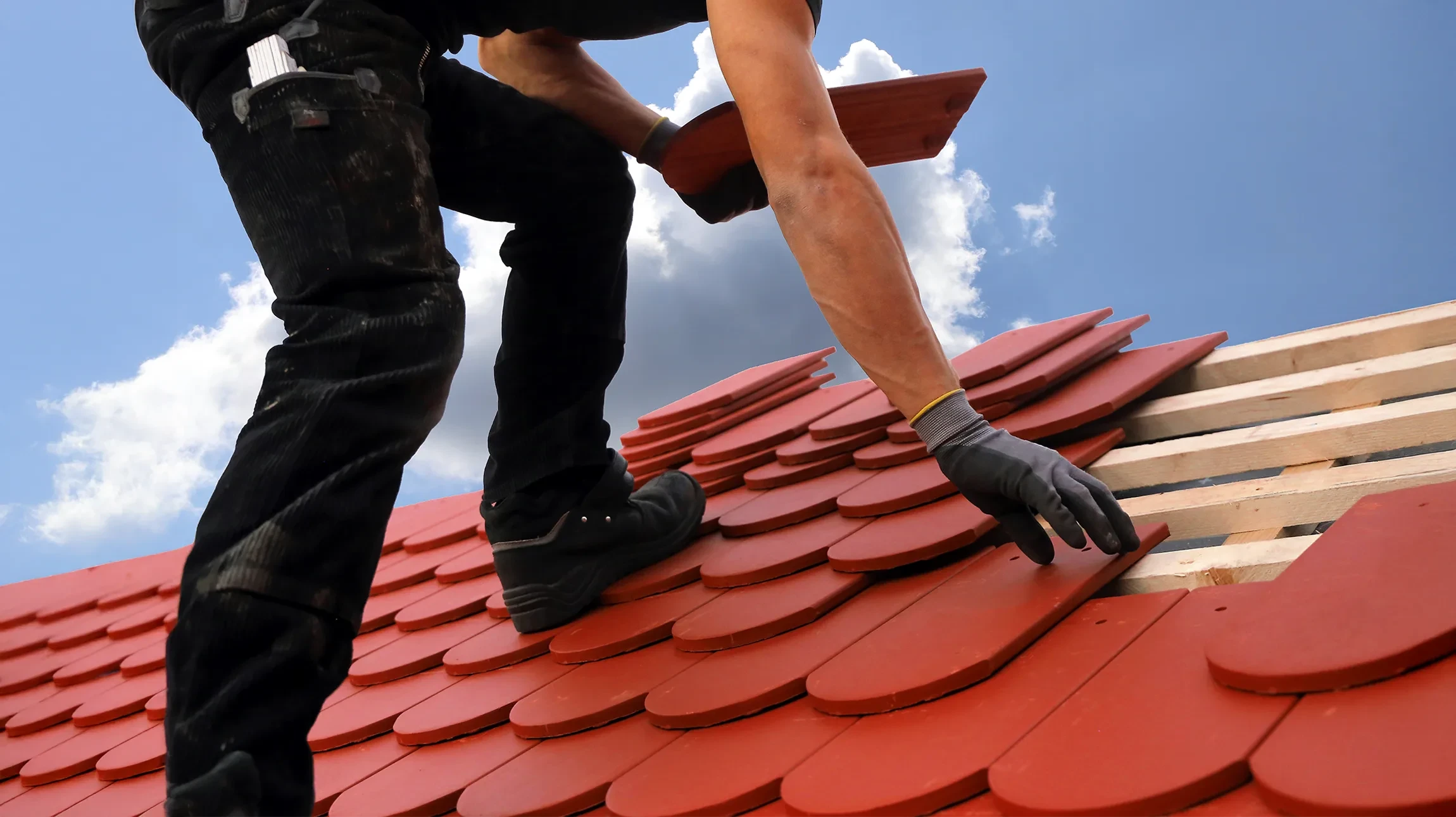 Chantier de toiture en cours avec pose de tuiles canal rouges sur charpente bois