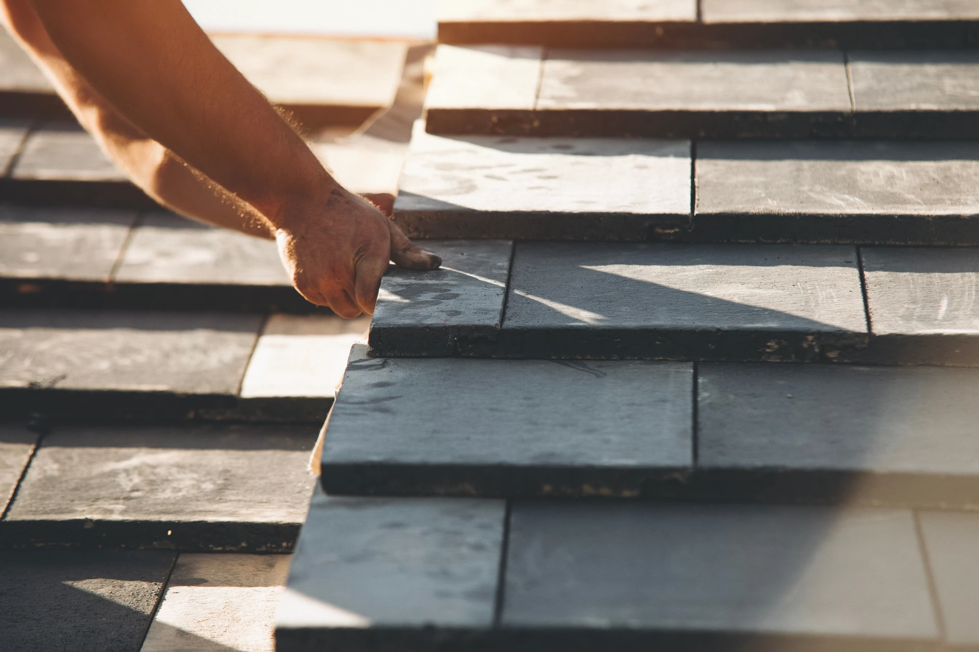 Ouvrier couvreur travaillant sur toiture ardoise d'une maison traditionnelle en pierre
