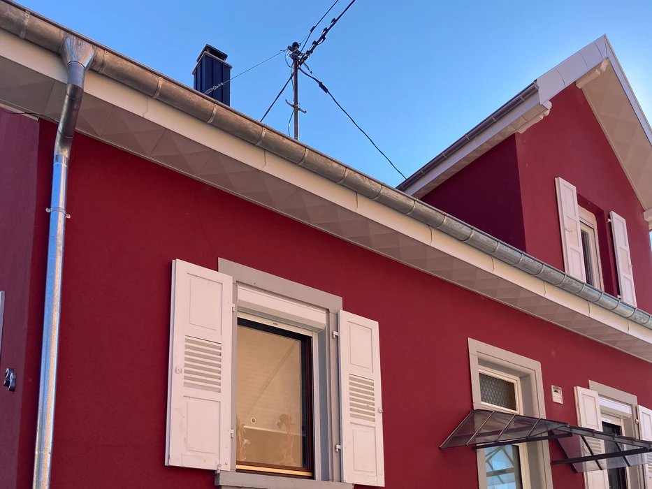 Toiture plate moderne avec lucarne rectangulaire vitrée à cadre noir, installée sur membrane d'étanchéité grise