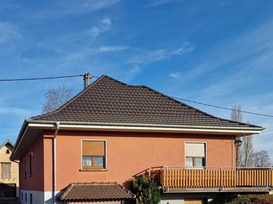 Vue extérieure d'un bâtiment moderne en construction avec façade en panneaux composites gris et structure métallique apparente