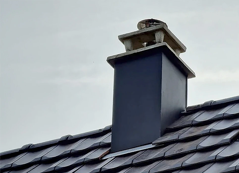 Chantier de construction extérieur avec toiture métallique bleue en cours d'installation sur charpente bois