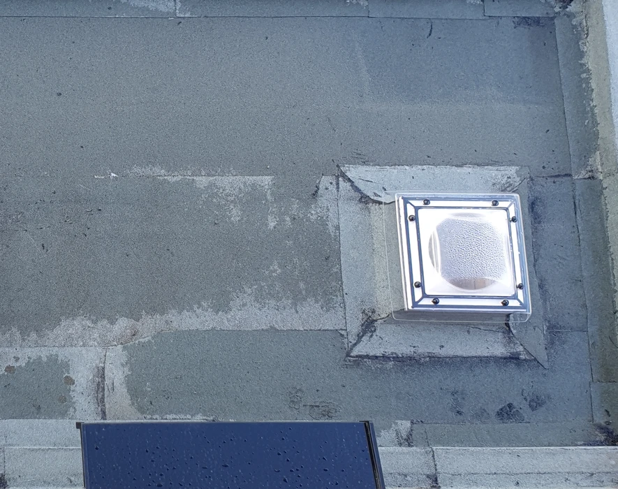 Chantier de toiture-terrasse en cours d'achèvement avec étanchéité bitumineuse posée, relevés d'étanchéité en périphérie et évacuation d'eaux pluviales installée